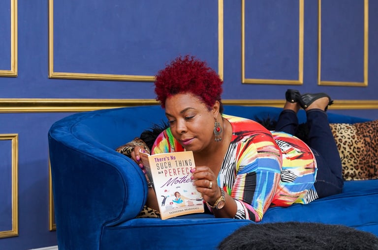 picture of author yasheema lying on a couch reading a book 