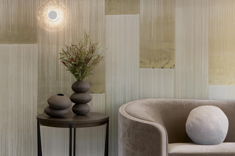 Modern living room featuring a velvet sofa, marble side table with ceramic vases, and textured wallpaper.