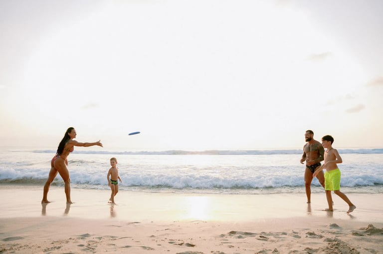 Family playing frisbee together during sunset at Dreamland Beach Bali captured in a candid family photography session.