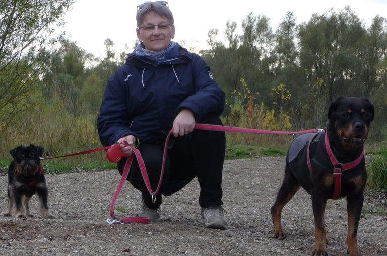 a woman in a blue jacket is holding a dog on a leash