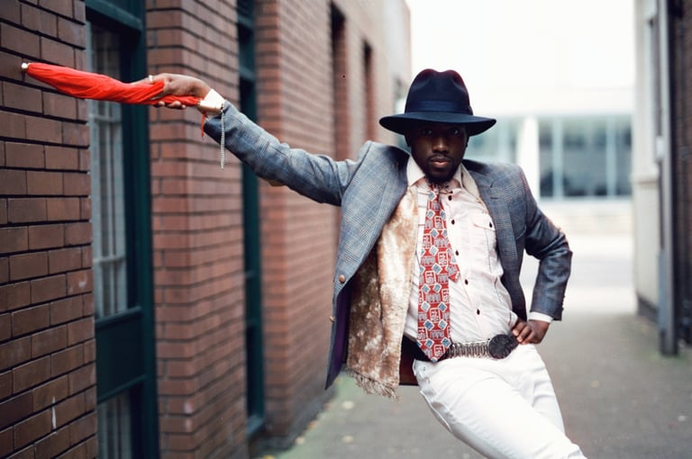 a man in a suit and hat holding a red umbrella