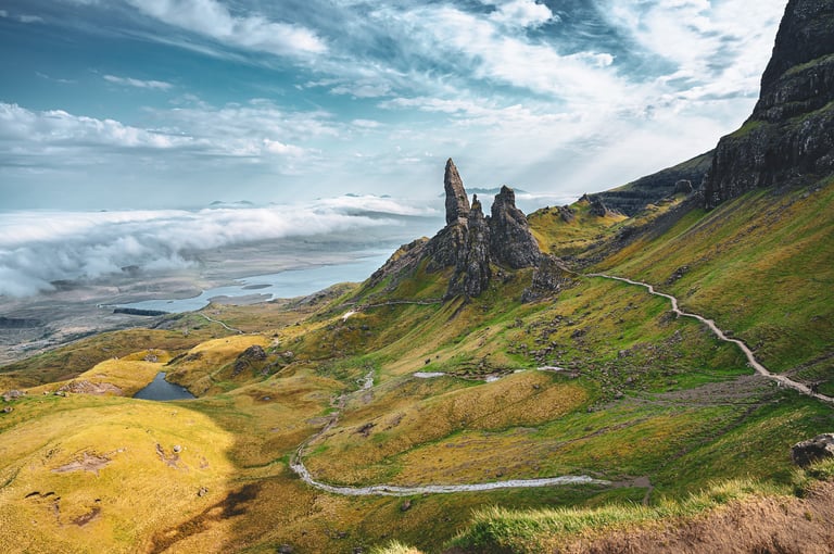 L'Old Man of Storr se dresse majestueusement au milieu des collines verdoyantes de l'île de Skye, sous un ciel dramatique.