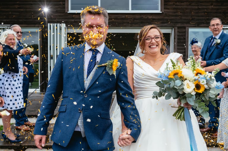 Bride and groom laughing as confetti is thrown at Llanerch Vineyard wedding in South Wales, captured by Owen Mathias