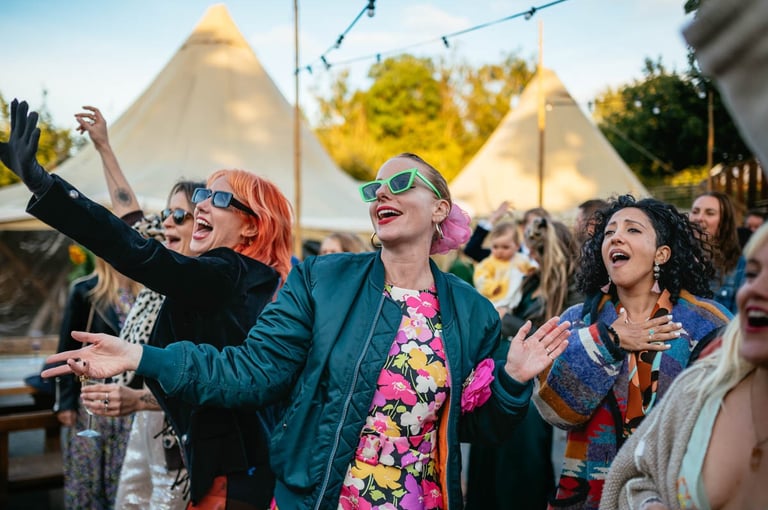 Wedding guests dancing and singing at Ceridwen Centre outdoor wedding in South Wales, captured by photographer Owen Mathias
