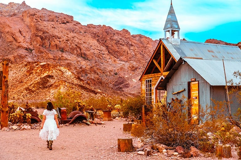 a woman in a white dress walking down a dirt road
