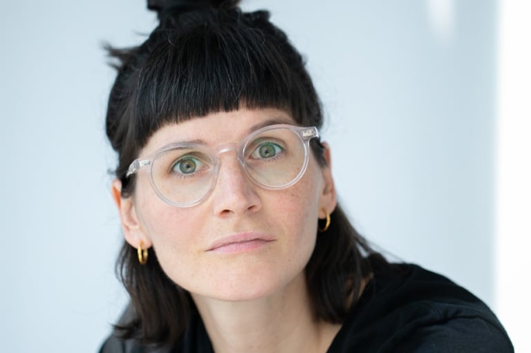 eine Frau mit Brille und schwarzen Haaren, die zum Zopf hochgesteckt sind