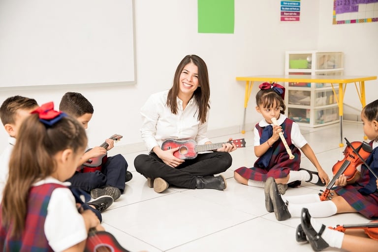 Teacher sitting with students in a classroom music circle.