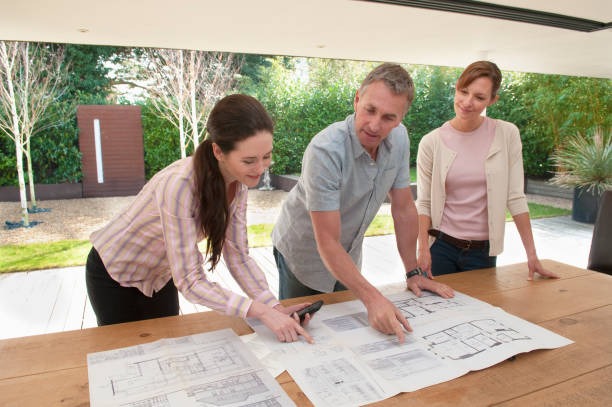 People reviewing landscape plans on an outdoor table
