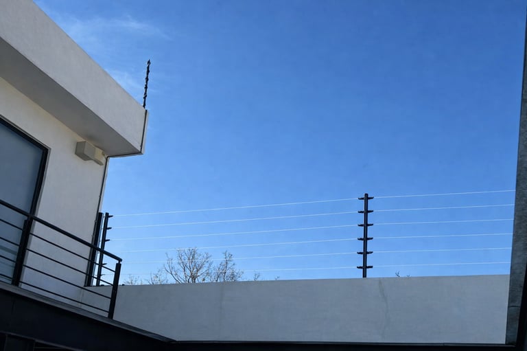 Cerco eléctrico de alto voltaje instalado en un muro perimetral residencial.