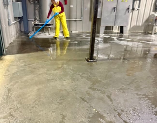 CLEANING SPECIALIST DEEP CLEANS THE FLOOR AT AN INDUSTRIAL FACILITY