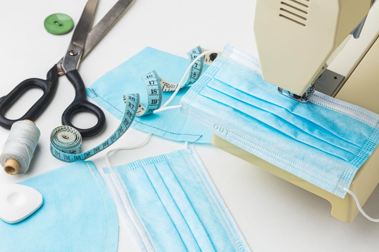 sewing-machine-stitching-medicated-masks-scissors-lying-on-table