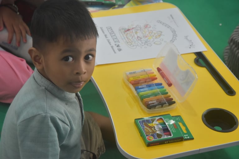 A photographer takes a picture of a boy drawing at a folding table
