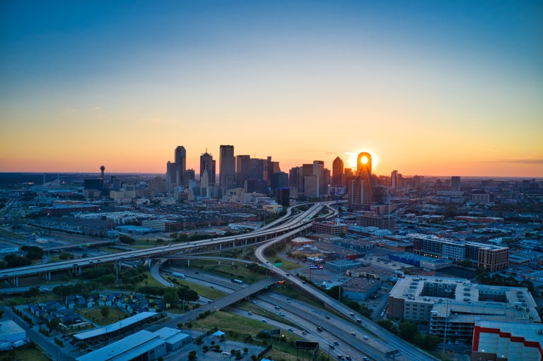 a city skyline with a sunset over a highway