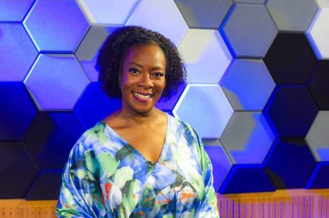 a woman in a blue dress standing in front of a wall with hexagon