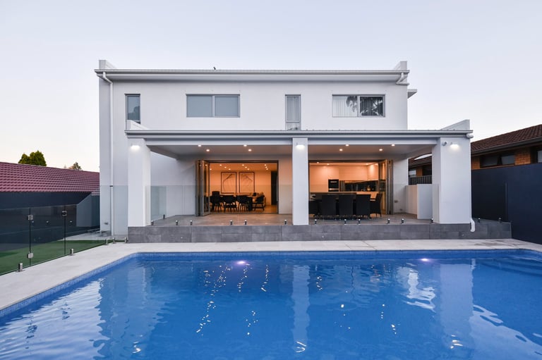 modern white home with outdoor entertainment and pool in foreground