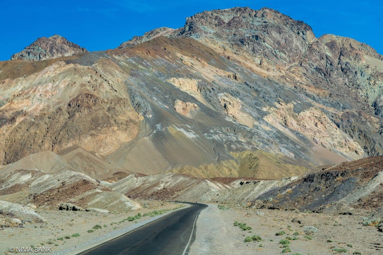 a road fading into the colorful facades of artists palette in death valley national park
