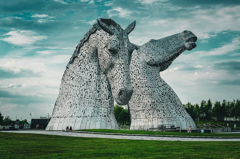 Les Kelpies, sculptures géantes de têtes de chevaux en acier, s'élèvent majestueusement sur un fond de ciel nuageux.