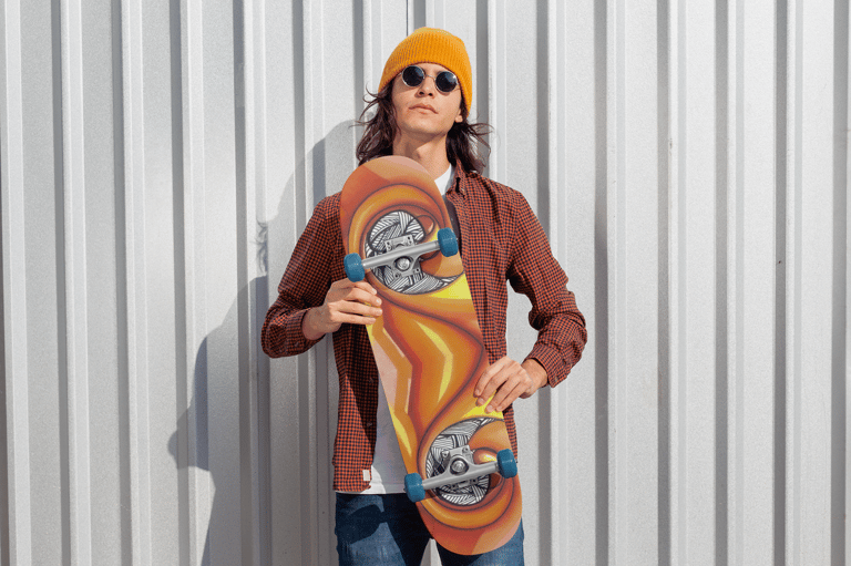 a man in a yellow hat and sunglasses holding a skateboard