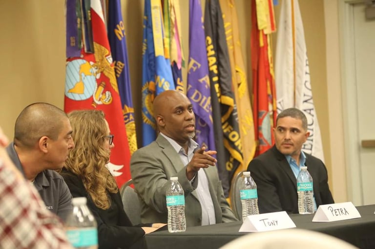 Lee A Jones in a suit and tie is sitting at a table  with a microphone