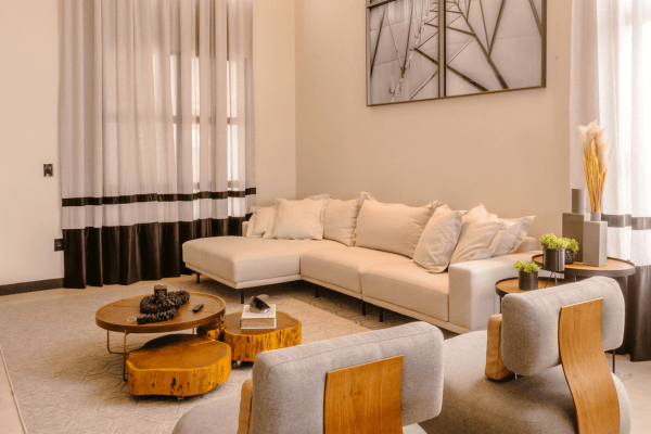 Modern minimalist living room featuring a cream sectional sofa, wooden coffee tables, and contemporary decor.