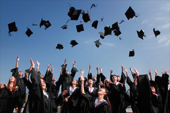 a group of graduates in black caps and gowns throwing their caps