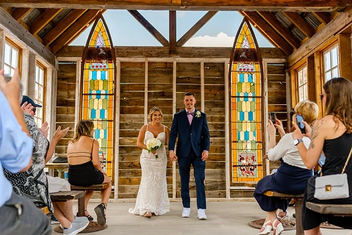 a bride and groom walking down the aisle of a church