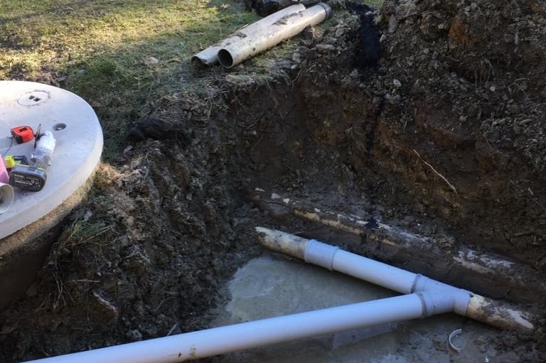 Drain repair with exposed underground pipes during excavation and replacement process