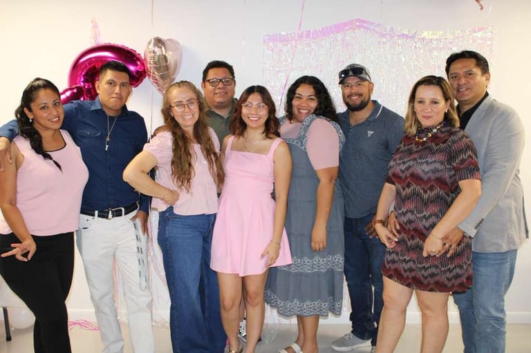 A group of smiling family and friends posing together at a pink-themed birthday party celebration.