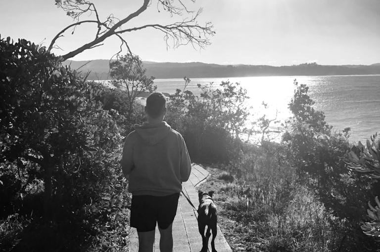 Tom Carolan walking his dog along a beach headland path