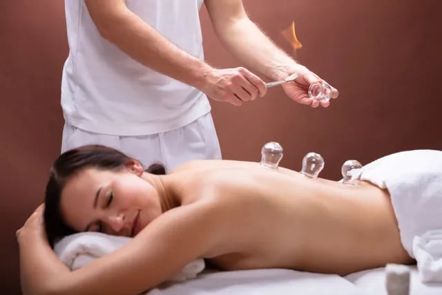 Terapeuta profesional que realiza terapia de ventosas de fuego en la espalda de una mujer para la re