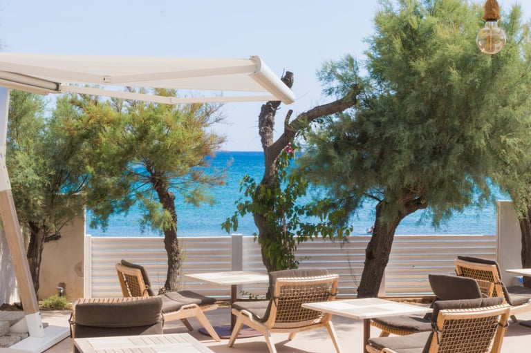 a patio with a table and chairs and a view of the ocean