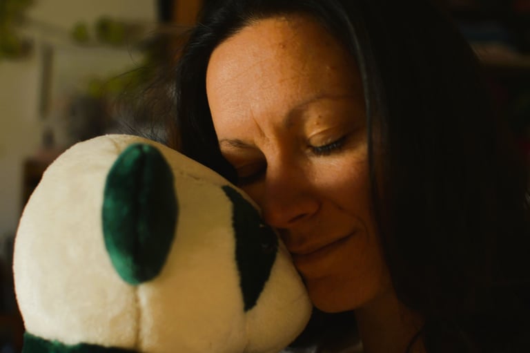 Autoportrait d’une femme serrant un doudou artisanal contre son visage, moment de réconfort