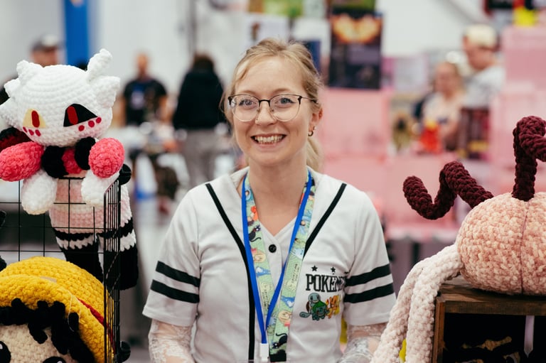 A very happy vendor stands with the crochet art she is selling.