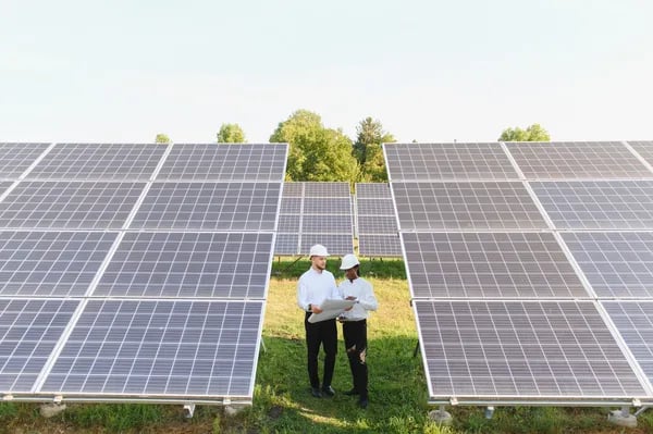 Fotografía de un hombre y una mujer con casco de protección parados en medio de paneles solares en S