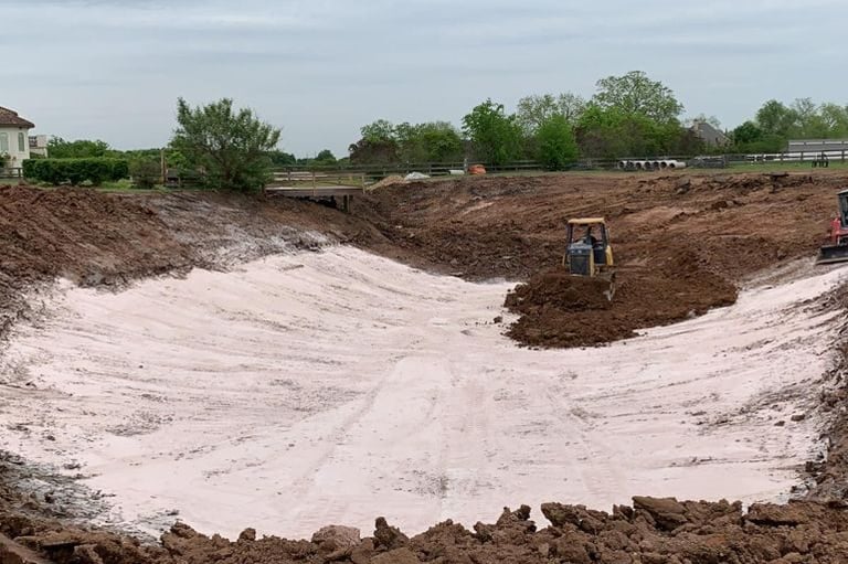 Excavator digging natural lake with bentonite clay liner, eco-friendly natural build | Aqua Vitae