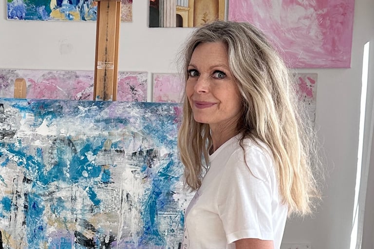 Artist Jeannie Berglund in her studio in front of a painting in teal, gold and white