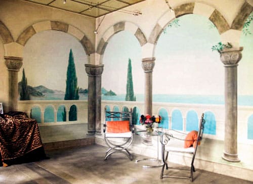 Interior of tile showroom with ocean mural, faux sandstone walls, arches and inlay concrete floor.