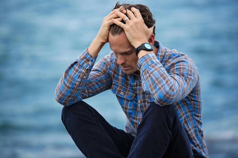 a man sitting on a bench with his hands on his head