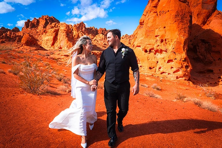 a bride and groom walking through the desert