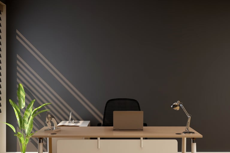 Modern home office with a minimalist wooden desk, ergonomic chair, and laptop against a dark grey wall.