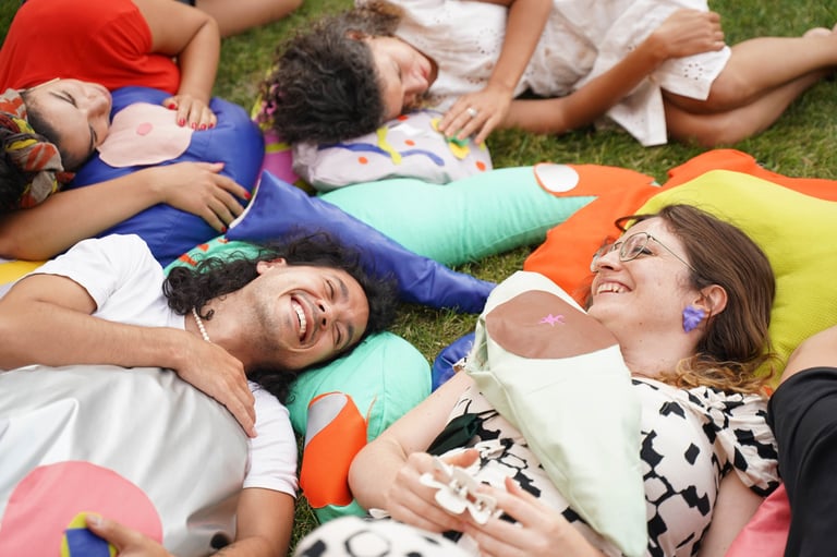 People laugh and play on soft sculptures of body parts.