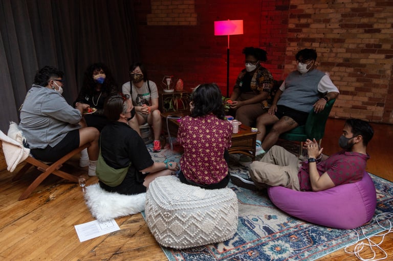 About 10 people sit on soft seats talking around a coffee table.