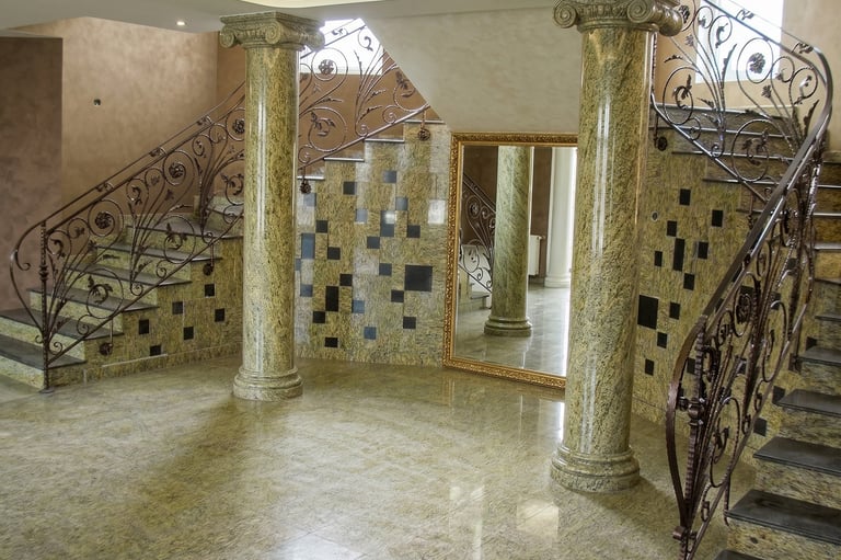 Luxury interior with marble columns, granite flooring, and an ornate wrought iron staircase.