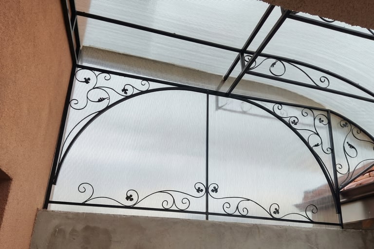 Custom decorative wrought iron balcony railing with a polycarbonate canopy roof for outdoor weather protection.