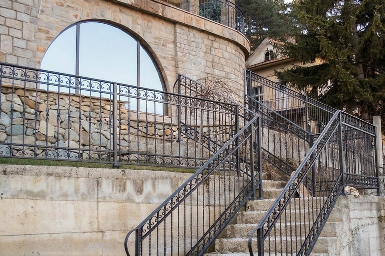 Custom wrought iron railings and outdoor stairs for a stone exterior luxury home.