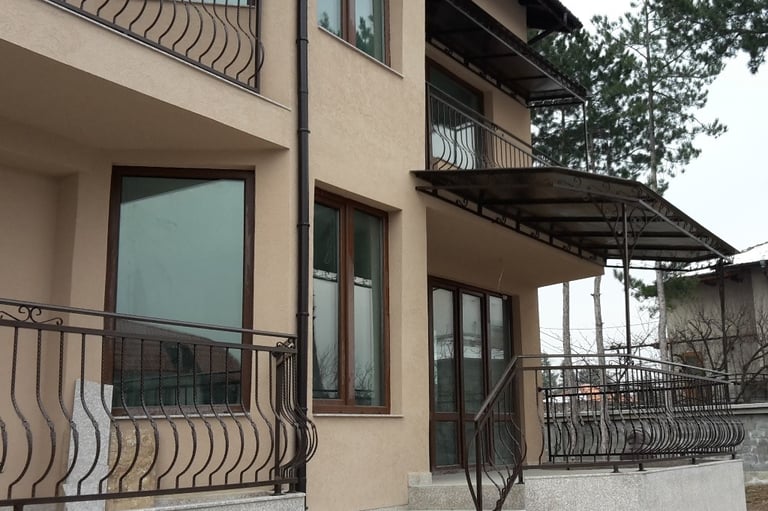 Modern house exterior with stucco walls and decorative wrought iron balcony railings.