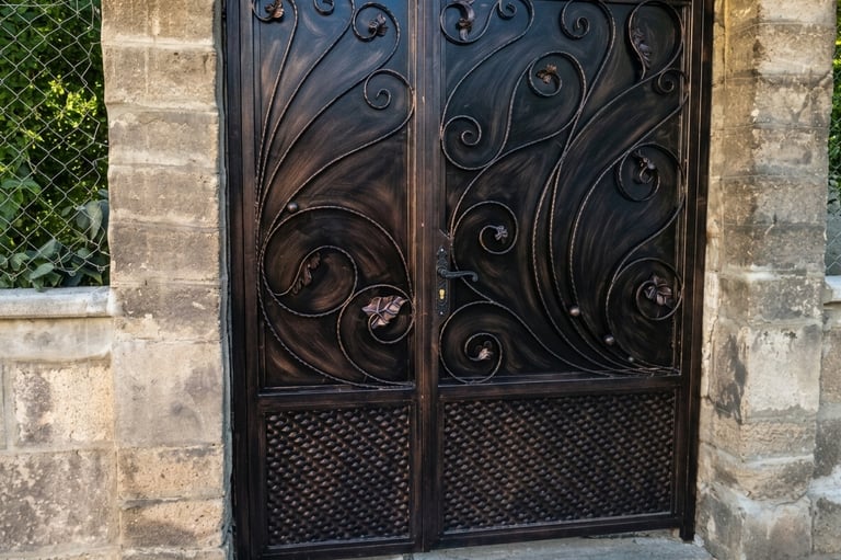 Ornate black and bronze wrought iron gate with elegant decorative scrollwork and leaf details.