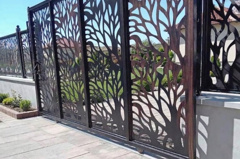 Modern laser-cut sliding gate with a decorative tree branch design on a stone patio.