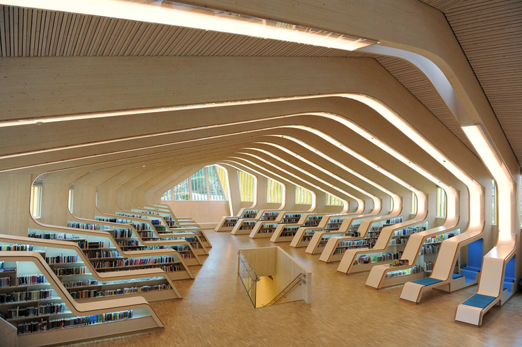 Modern Vennesla Library interior featuring curved wooden ribs and integrated bookshelves with seating.