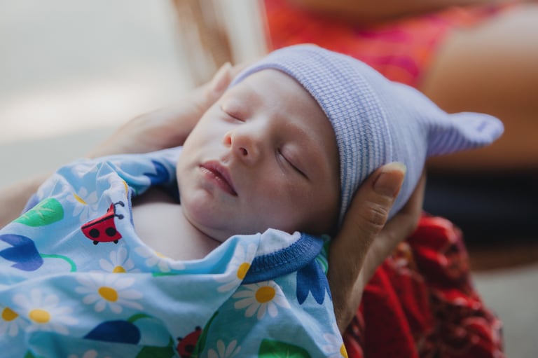 Photographie d'un bébé endormi entre les mains de sa mère, par Zohra Elmes